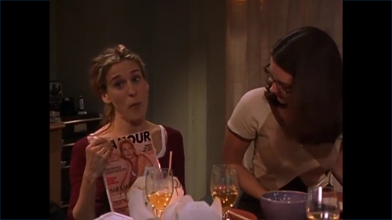 Carrie is holding up a copy of Glamour Magazine. Charlotte is looking directly at the cover.