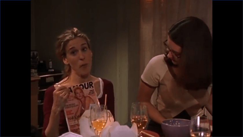 Carrie is holding up a copy of Glamour Magazine. Charlotte is looking directly at the cover.